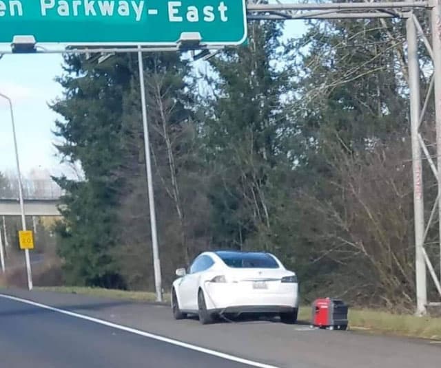 Tesla car charging from a portable generator on the side of a road